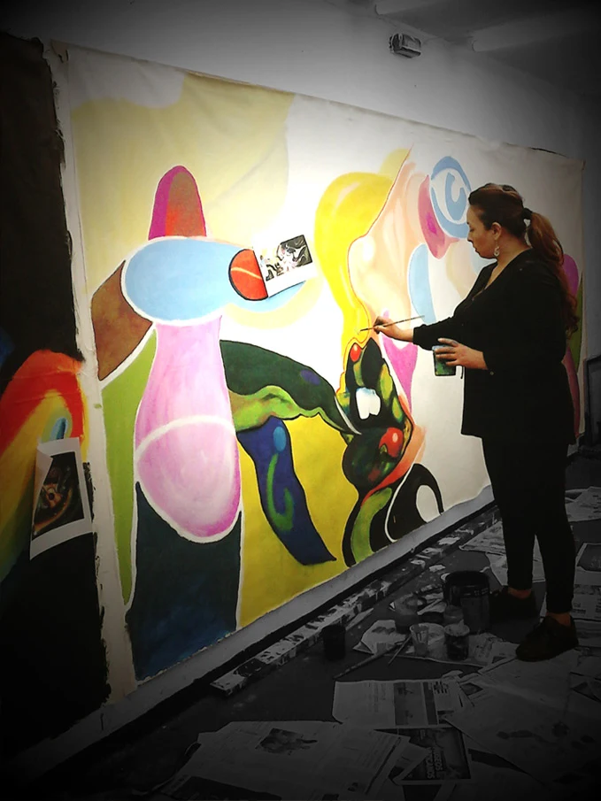 Artist working on a large colorful abstract figure mural