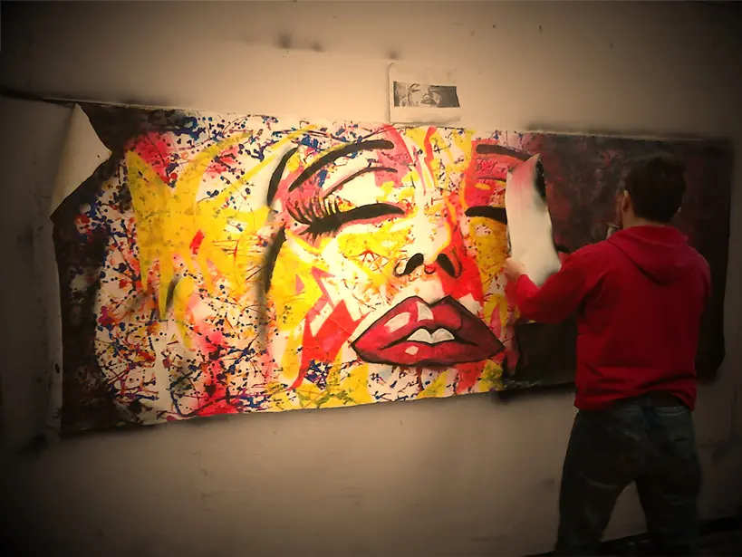Artist painting a large expressive mural in progress